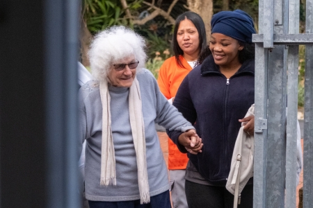 mobile frail carer helping an elderly person to an event