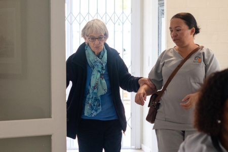 mobile frail carer helping an elderly person through the door